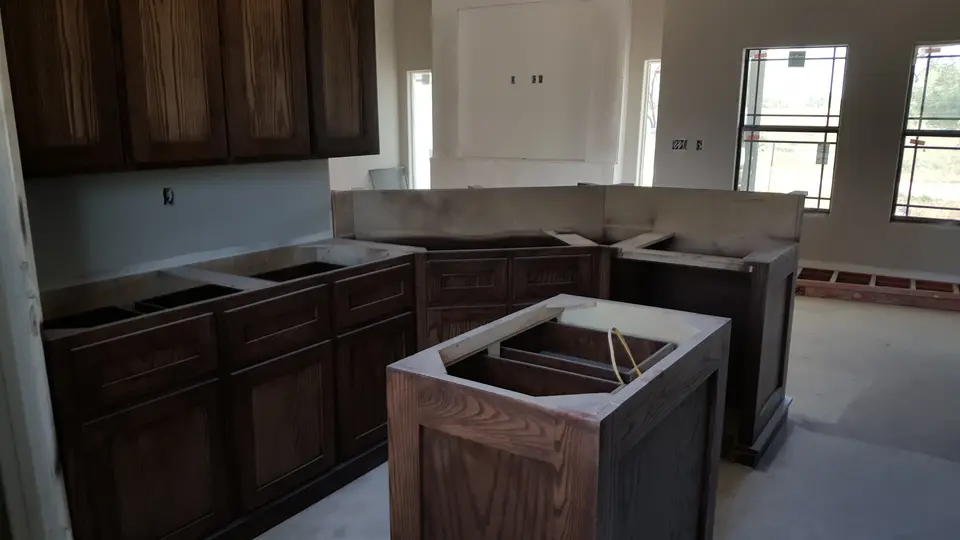 Kitchen cabinet and island installation showing custom dark wood millwork.