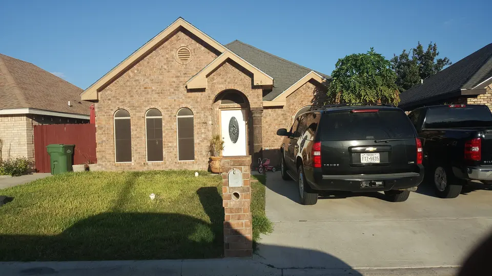 Completed Better Builders brick home with triple arched windows and stone detailing.