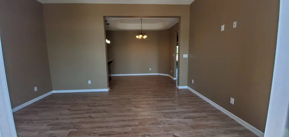 Finished Better Builders living area with wood-look tile flooring, neutral walls, and an open connection to adjoining interior spaces.