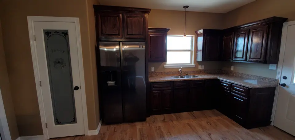 Finished Better Builders kitchen with custom wood cabinetry, built-in storage, granite surfaces, and coordinated flooring.