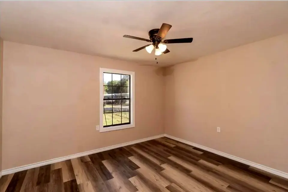 Finished Better Builders bedroom with wood-look flooring and a ceiling fan.