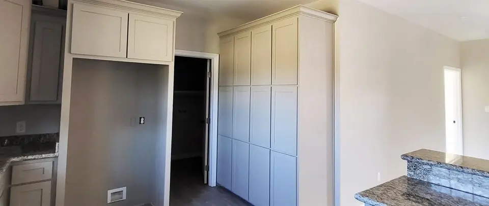 Built-in white pantry and utility cabinets with a granite counter.