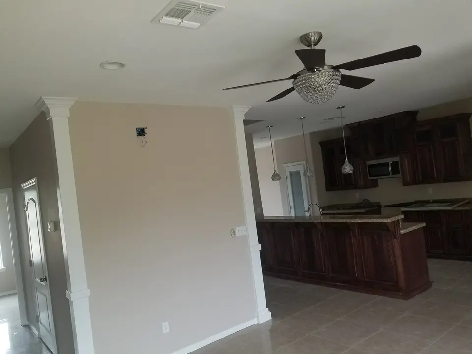 Open living area facing a custom dark wood kitchen during final interior finish work.