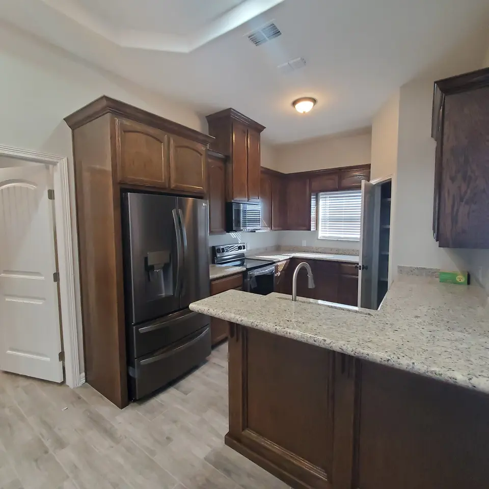Finished kitchen with dark wood cabinets, granite counters, and black appliances.