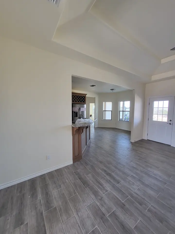 Finished open living area with wood-look flooring and a view toward the kitchen.