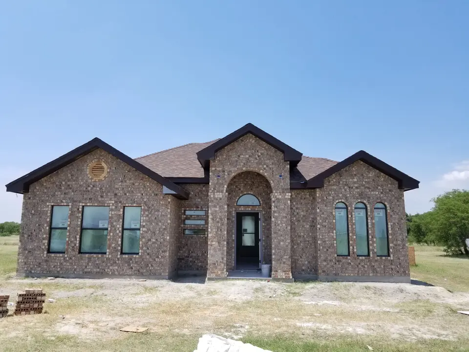 Front exterior of a brick Better Builders home with a tall arched entry and coordinated window groupings.