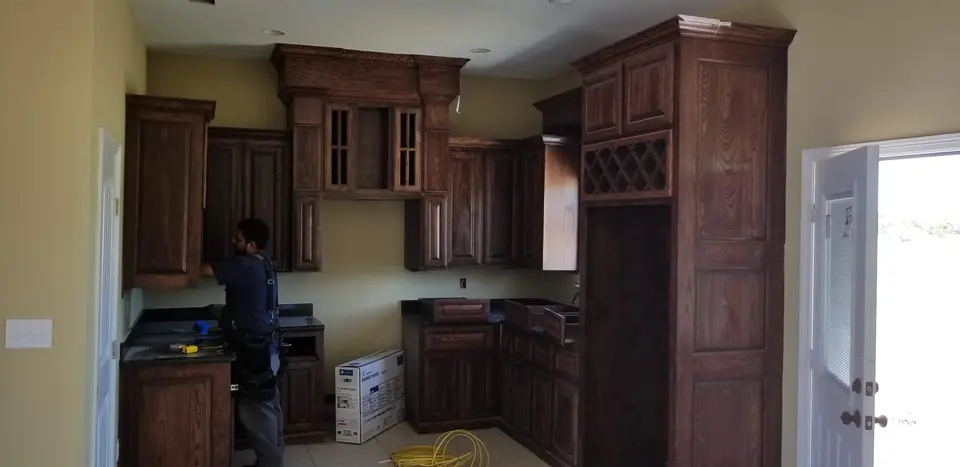 Dark wood custom kitchen cabinetry with built-in wine storage being installed inside a Better Builders home.