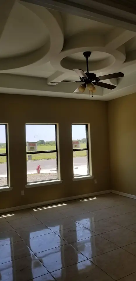 Finished living room with glossy tile flooring and a custom circular layered tray ceiling with a fan.
