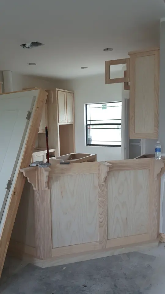 Unfinished custom wood cabinetry and island millwork being installed inside a Better Builders home.