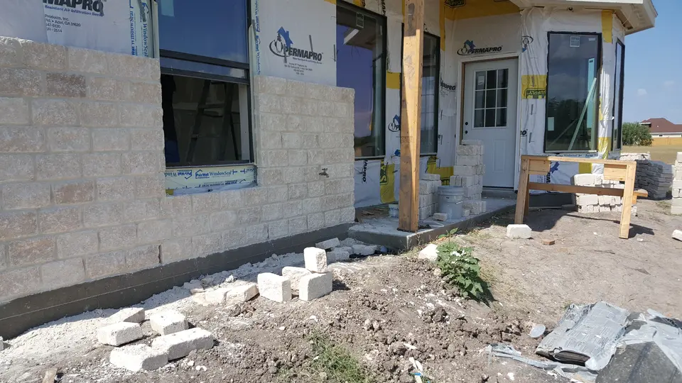Stone veneer installation underway around the front windows and entrance of a Better Builders home.