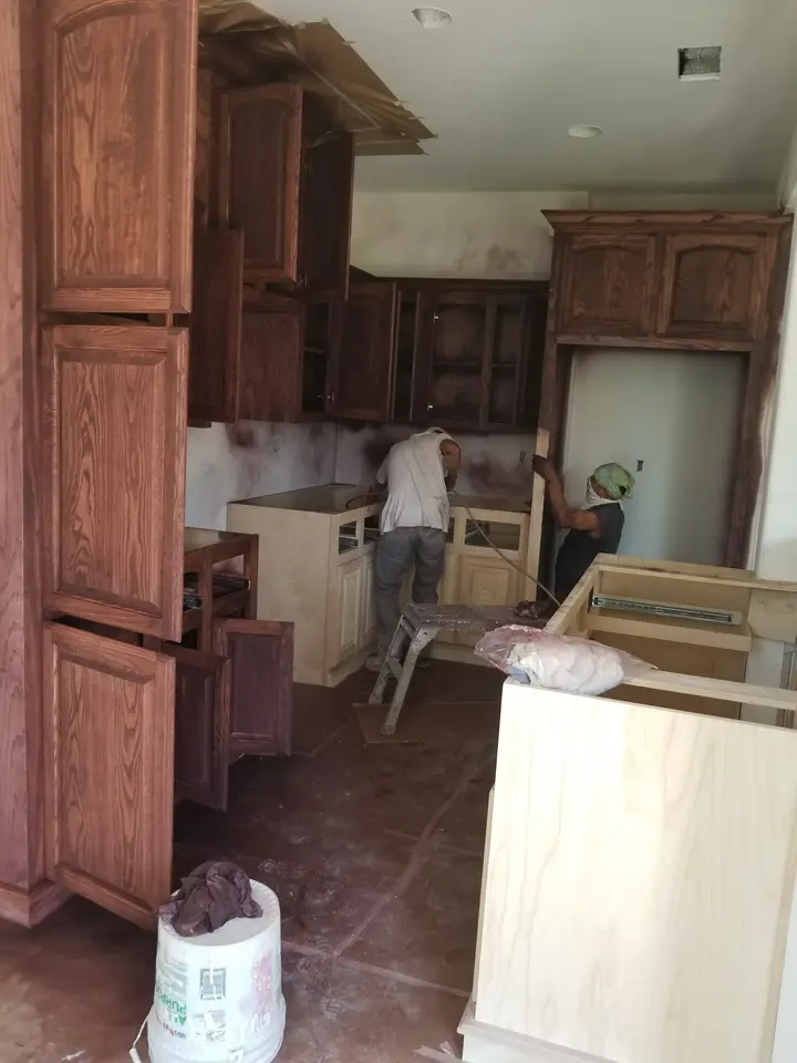 Custom stained wood kitchen cabinets and island components being fitted inside a Better Builders home.