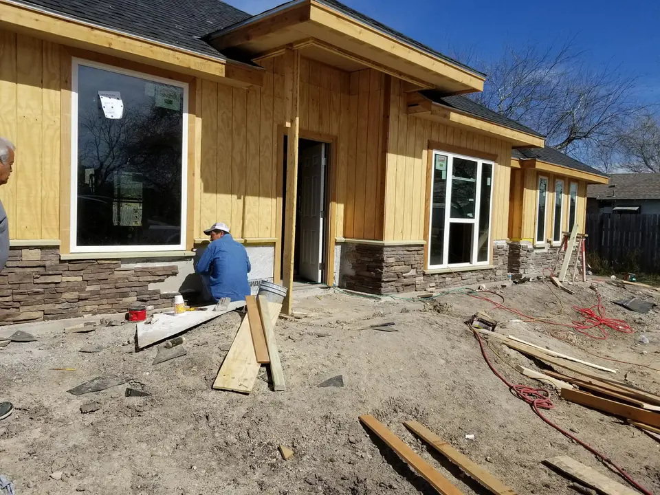 Craftsman installing stone veneer around the front entry and window wall of a Better Builders home.