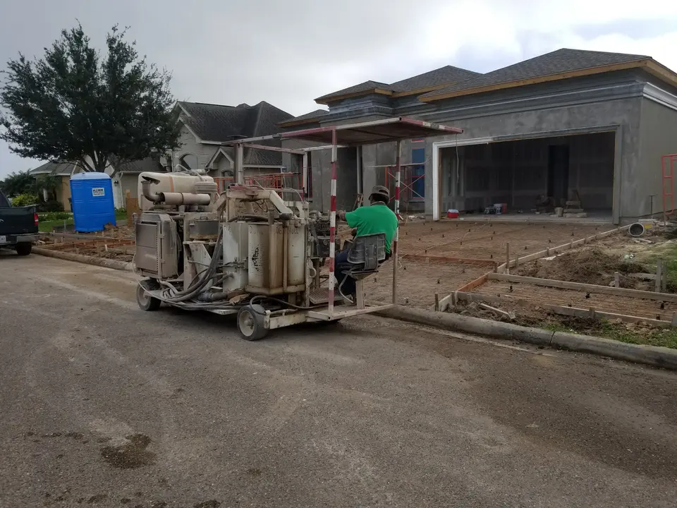 Stucco application equipment and a craftsman working in front of a custom Better Builders home during exterior finishing.