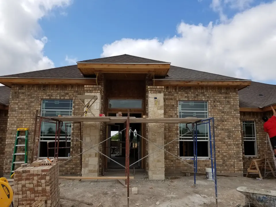 Front entry of a Better Builders home during brick and limestone masonry installation with scaffolding in place.