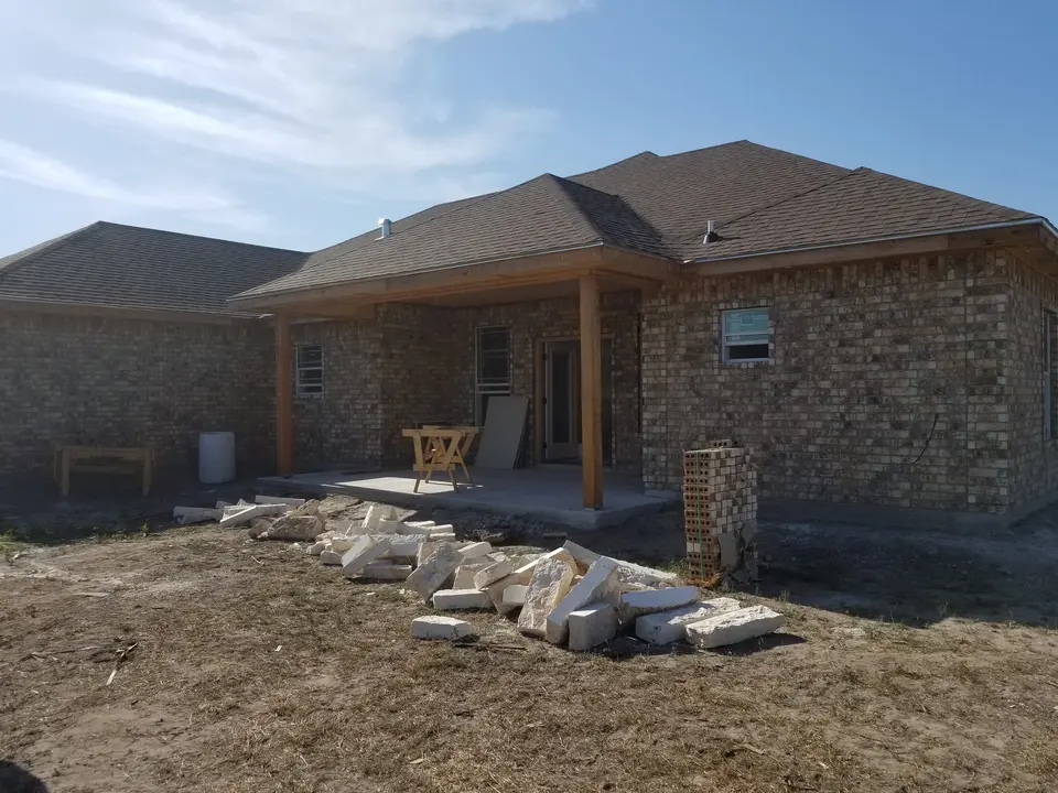 Rear brick exterior of a Better Builders home with a covered patio and masonry materials staged during construction.