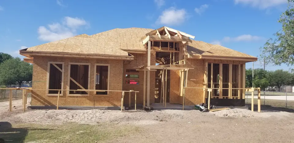 Front elevation of a Better Builders home with roof sheathing complete and a tall framed entry feature under construction.