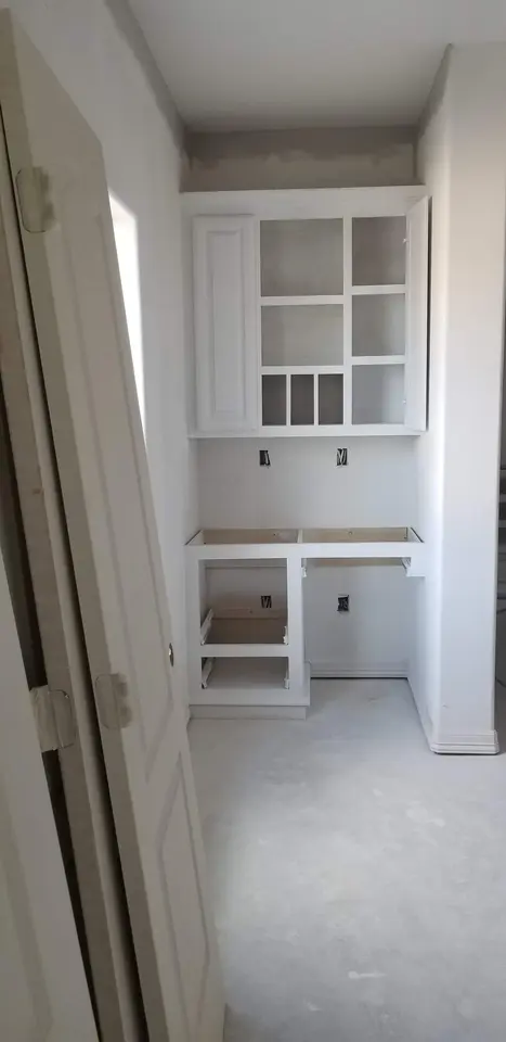 White built-in pantry cabinetry with open shelves and storage compartments inside a Better Builders home.
