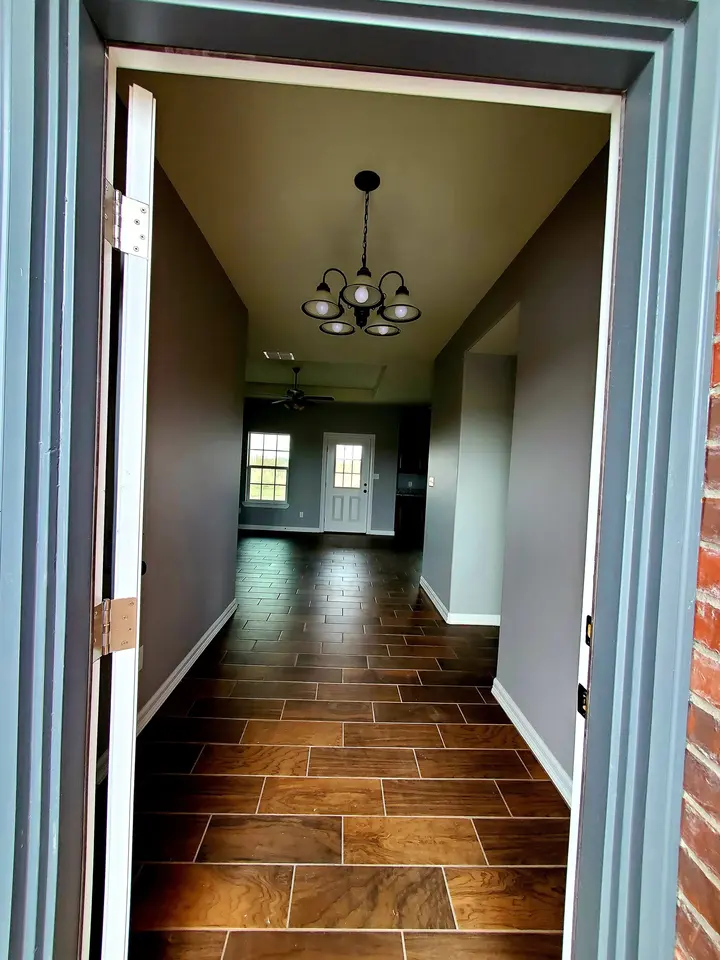 Finished entry hall inside a Better Builders home with gray walls, chandelier lighting, white trim, and wood-look tile flooring.