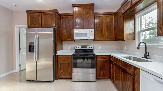 Completed Dewey Street kitchen with custom dark wood cabinetry, light countertops, and stainless appliances