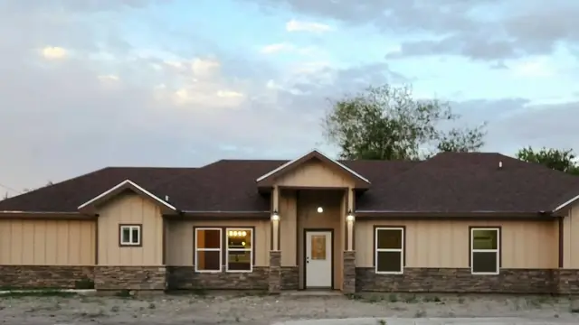 Completed front elevation of the Lucero Street Better Builders residence with layered rooflines, stone accents, garage, and covered entry